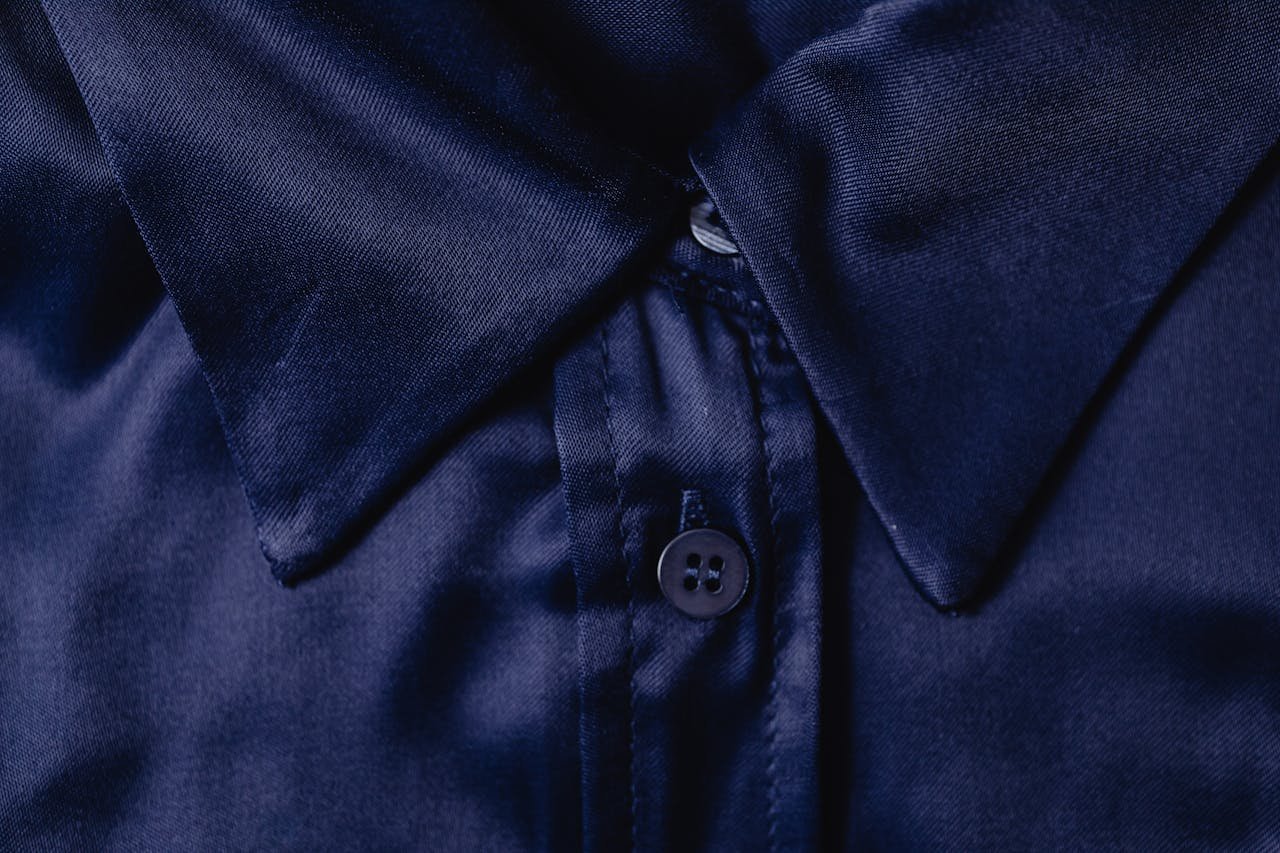 Detailed close-up of a blue silk shirt collar highlighting fabric texture and button.