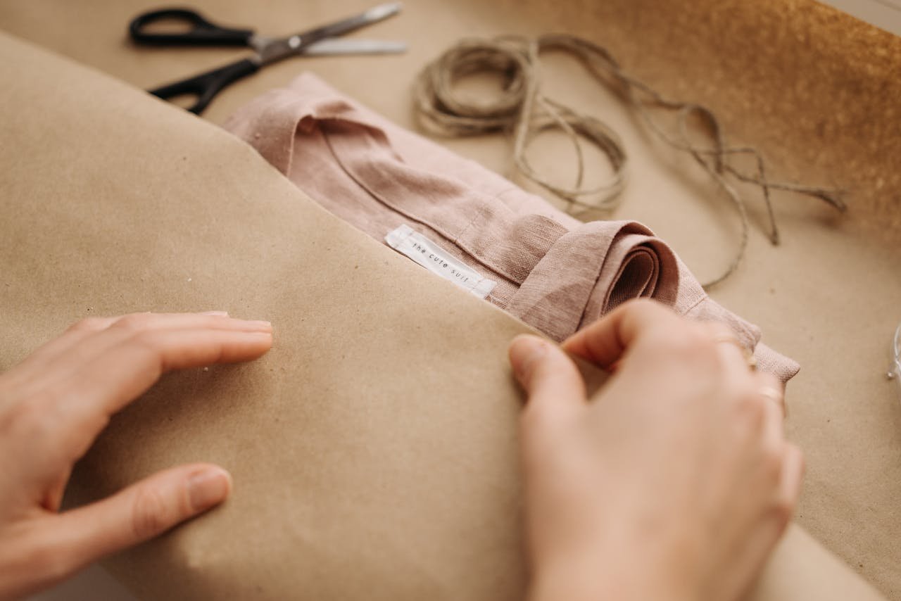 Offerings Close-up of hands wrapping a linen shirt with twine, showcasing craftsmanship and sustainable fashion.