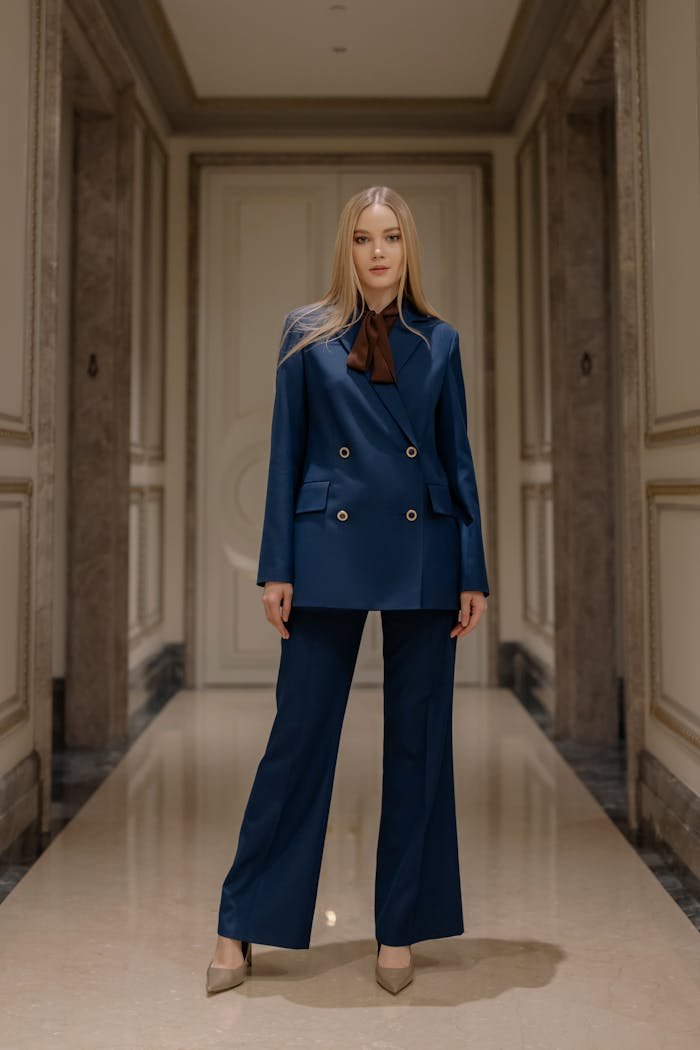 Stylish woman in a blue suit posing elegantly in a sophisticated hallway.