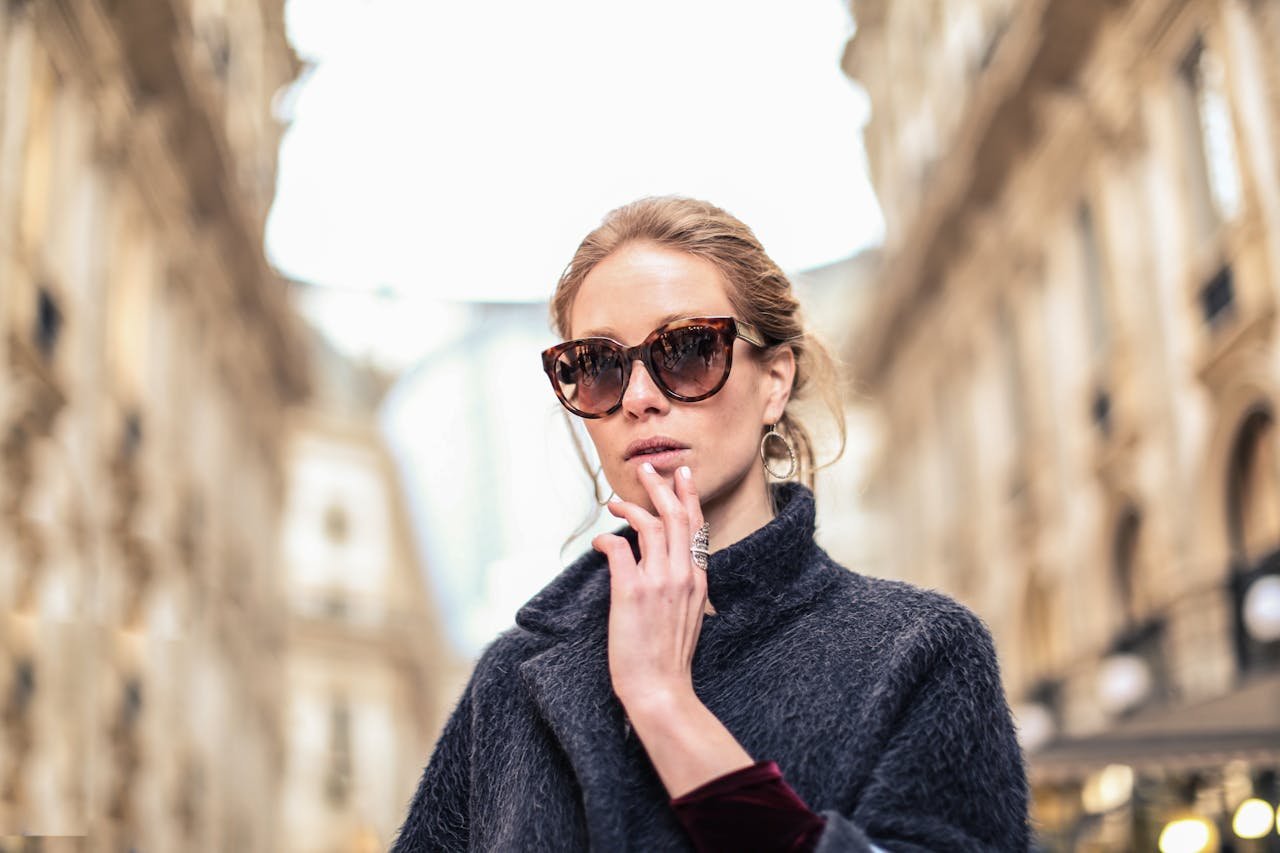 Elegant woman in sunglasses posing outdoors in a fashionable street setting.